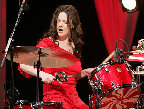 Meg White of The White Stripes playing drums during a live performance.