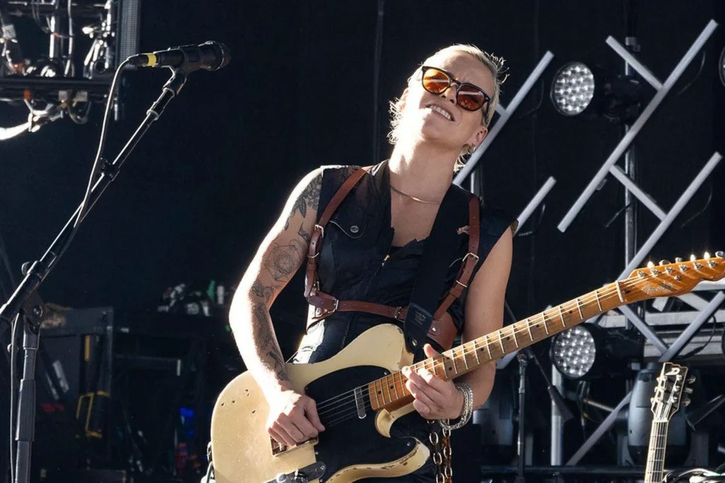Carmen Vandenberg performing live on stage with an electric guitar.