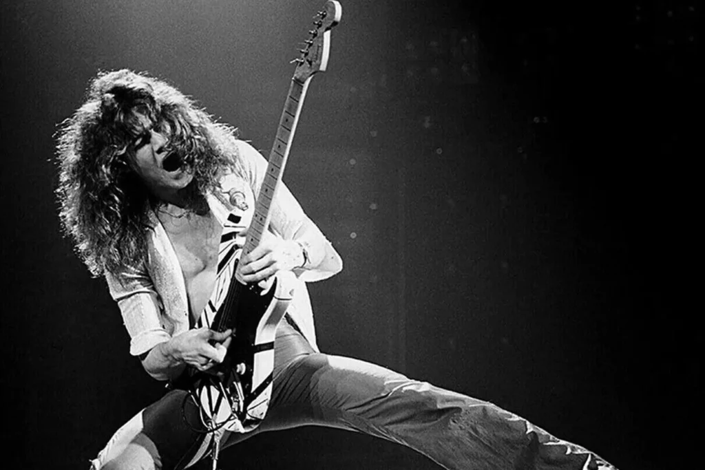 ddie Van Halen performing live on stage with his distinctive striped electric guitar.