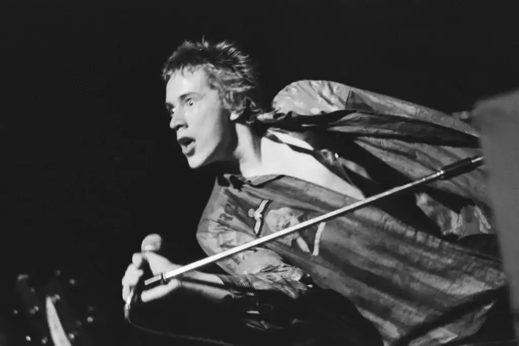 Johnny Lydon performing energetically on stage with a microphone.